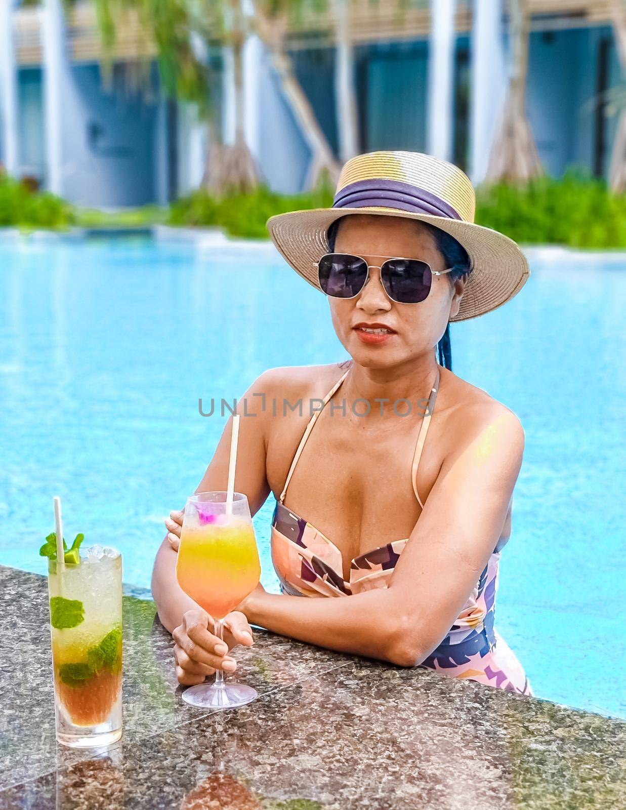 Asian women with hat and cocktail in hand relaxing in swimming pool, banner holiday vacation concept by fokkebok