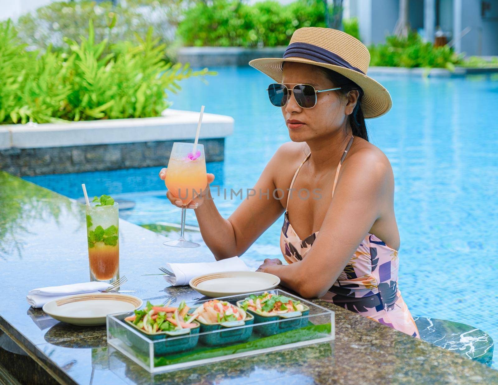 Asian women with hat and cocktail in hand relaxing in swimming pool, banner holiday vacation concept by fokkebok