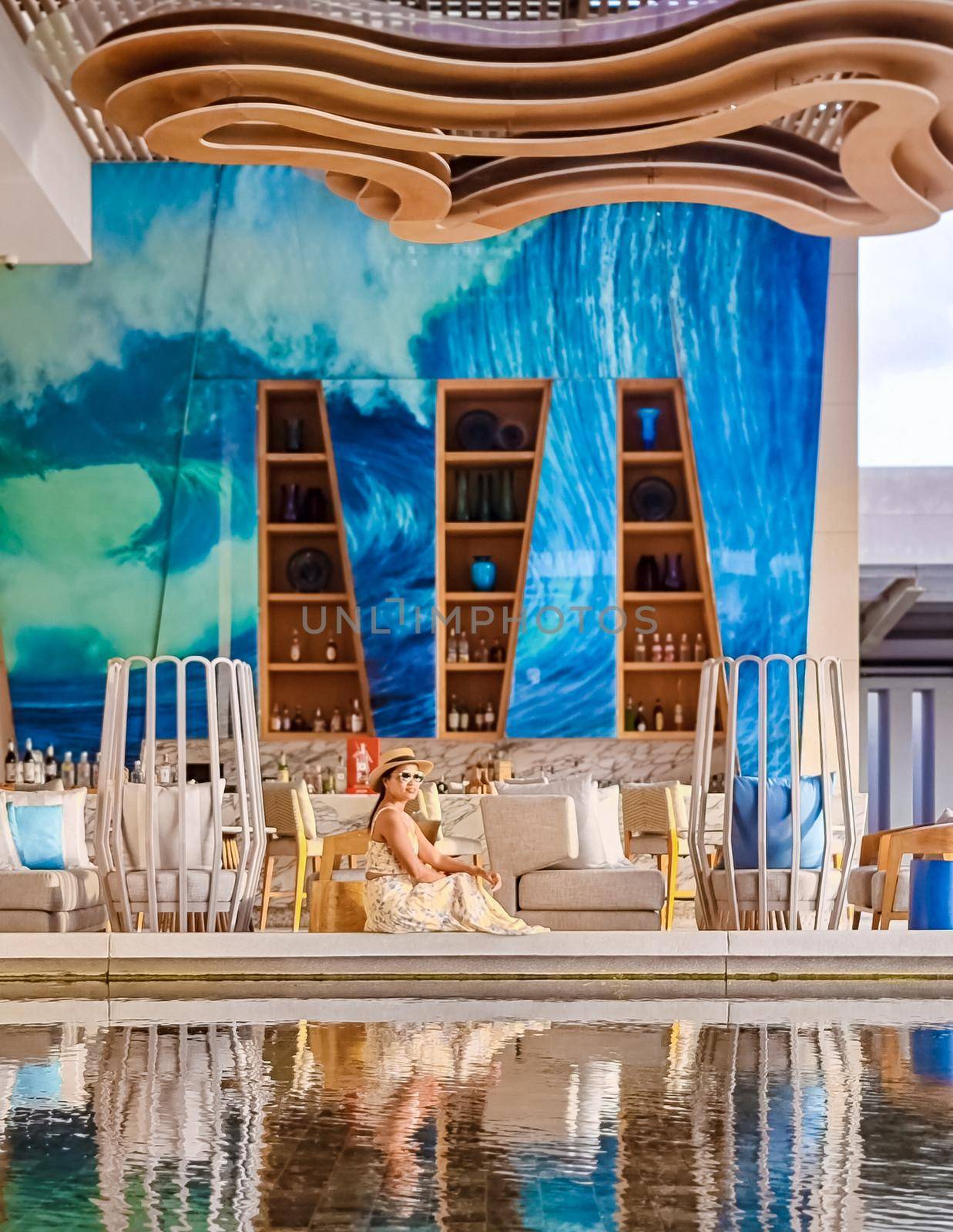 Asian women with hat relaxing at the bar during a luxury vacation in a hotel by fokkebok