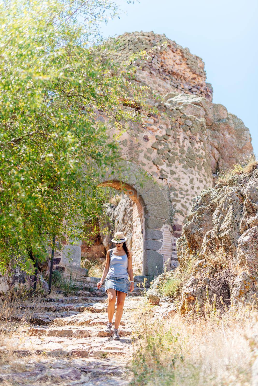 Tourist walking along a dry road in the middle of a medieval castle with an arch in the gate.