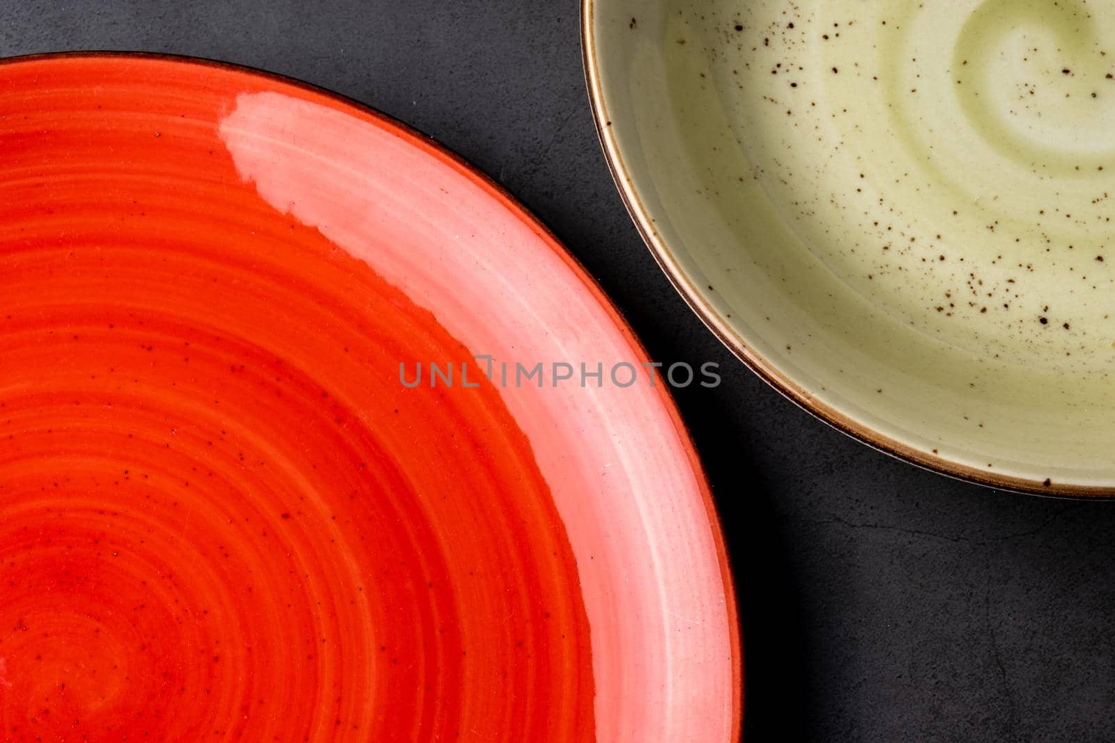 two empty colorful plates on black stone background