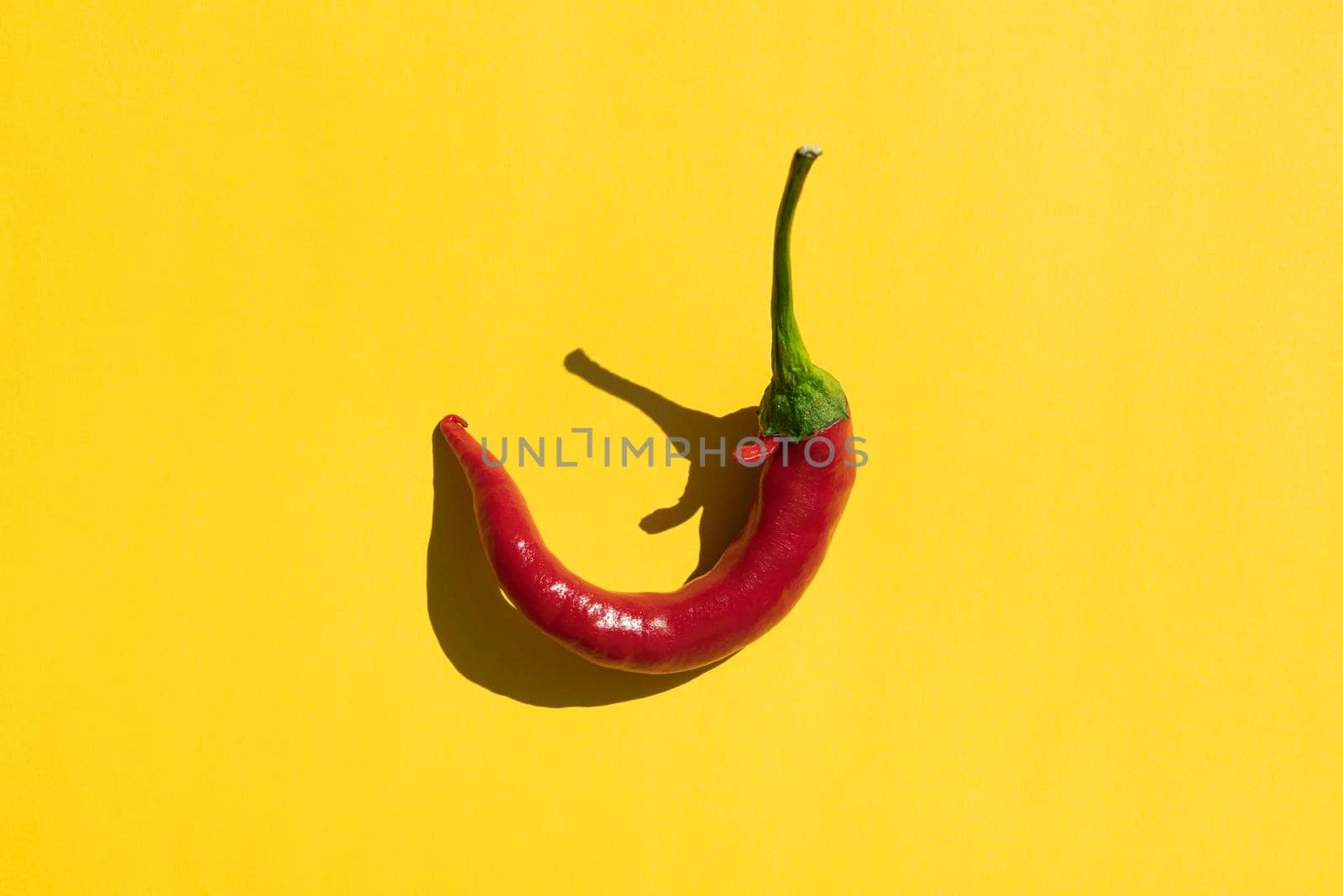 red hot pepper on a yellow background with a hard shadow. High quality photo