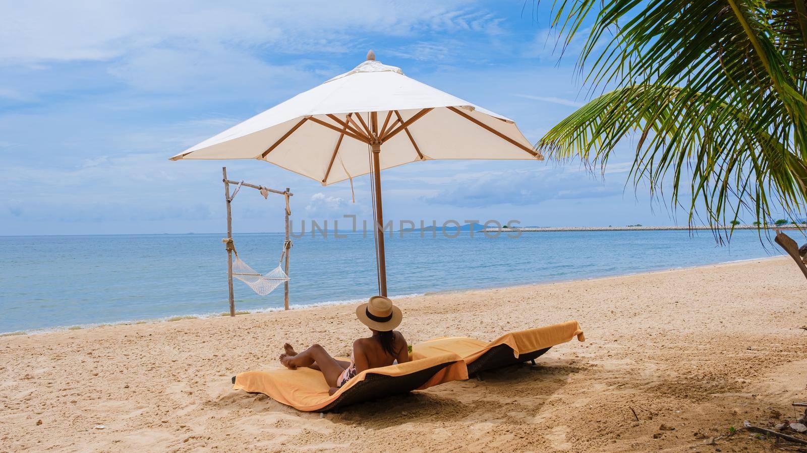 Women relaxing on a beach chair sunny day with hammock on beach in Pattaya Thailand Ban Amphur beach by fokkebok