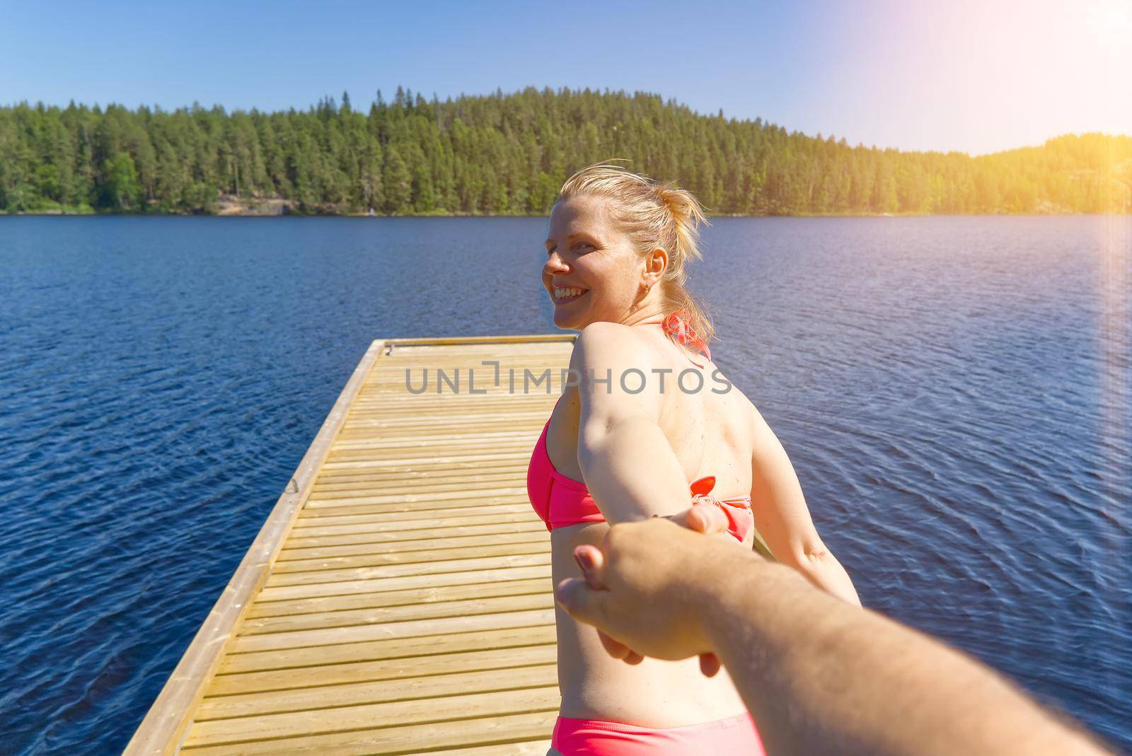 Follow me for a swim. Smiling girl runs along the pier and pulls a friend with him to swim. follow me travel concept