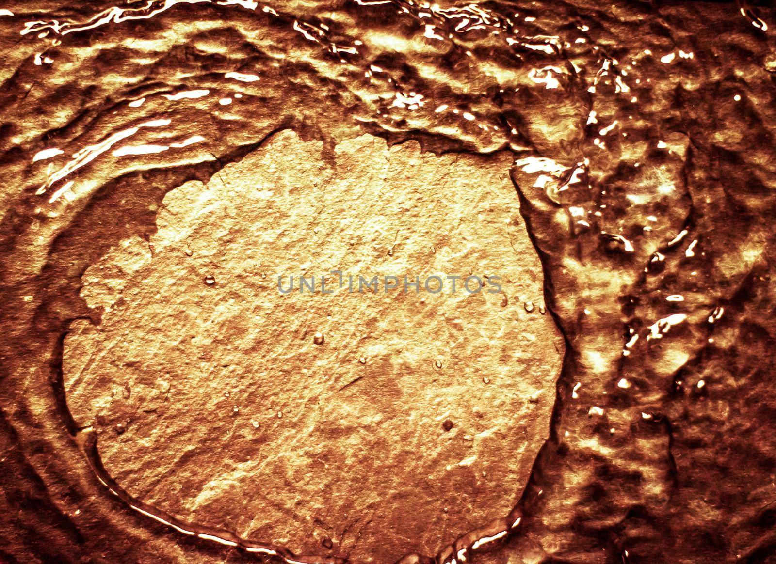 Flowing liquid on gold surface - luxury background and abstract design concept. Golden source