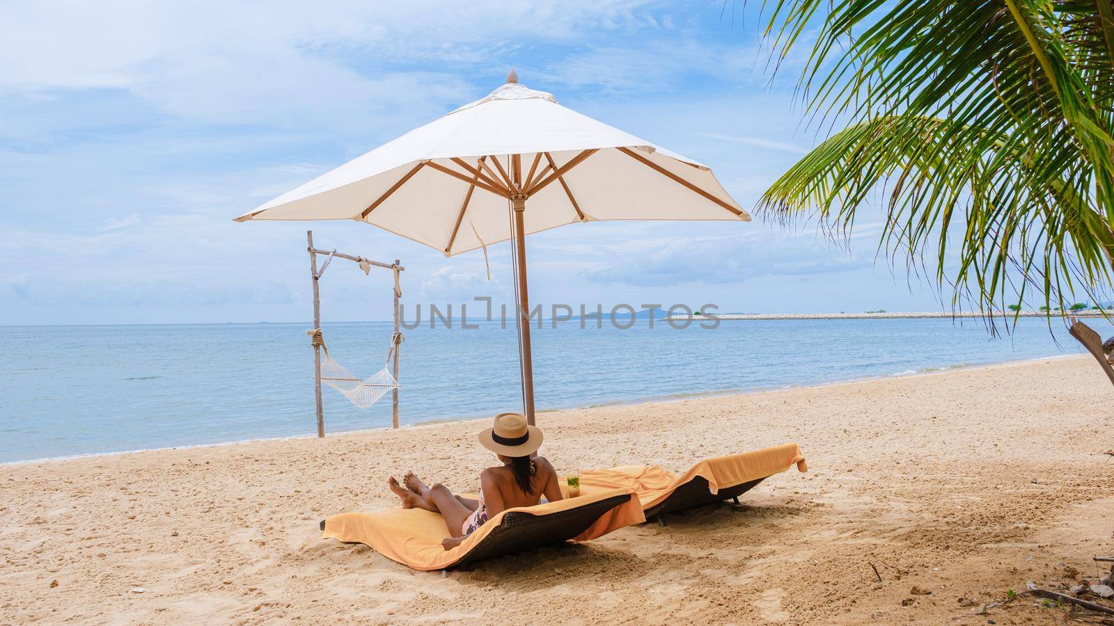 Women relaxing on a beach chair sunny day with hammock on beach in Pattaya Thailand Ban Amphur beach by fokkebok