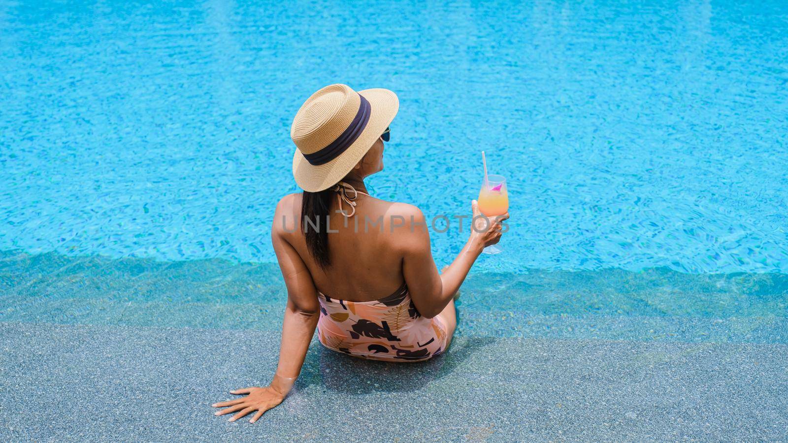 Asian women with hat and cocktail in hand relaxing in swimming pool, banner holiday vacation concept by fokkebok