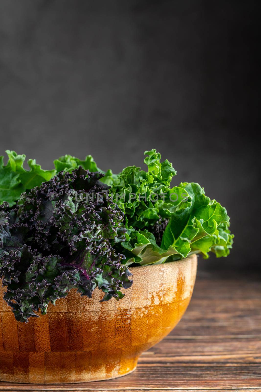 green leafy kale vegetable in bamboo bowl on wooden table background