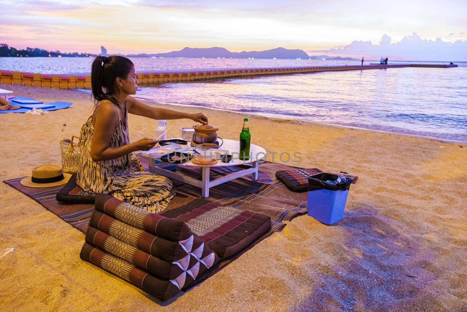 women bbq cooking noodle soup during sunset in Thailand Ban Amphur beach. relaxing with bbq Thai traditional on a tropical beach with palm trees and hammock during sunset