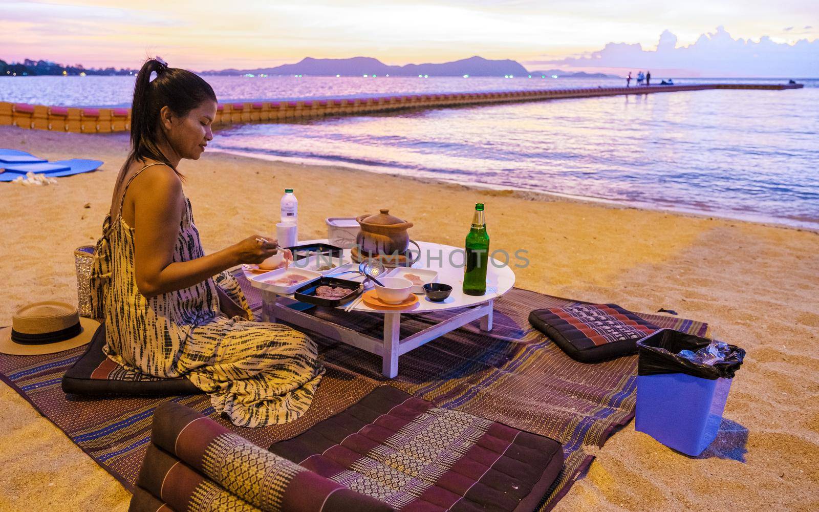 women bbq cooking noodle soup during sunset in Thailand Ban Amphur beach. relaxing with bbq Thai traditional on a tropical beach with palm trees and hammock during sunset