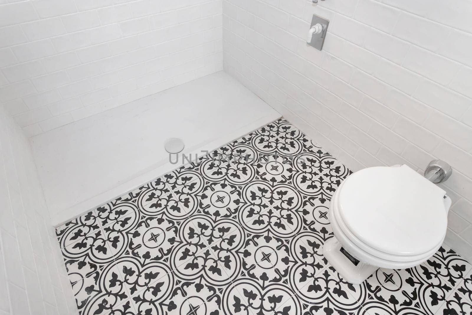 White ceramic toilet at luxury bathroom, with decored floor tiles. Italian style.
