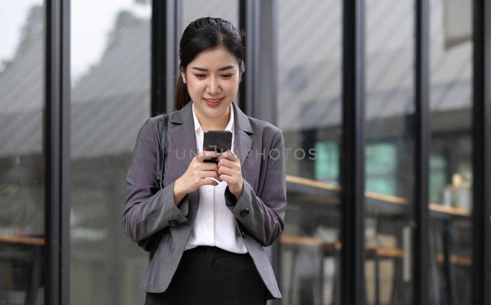 Portrait of a beautiful smiling woman using a mobile phone outdoors by wichayada