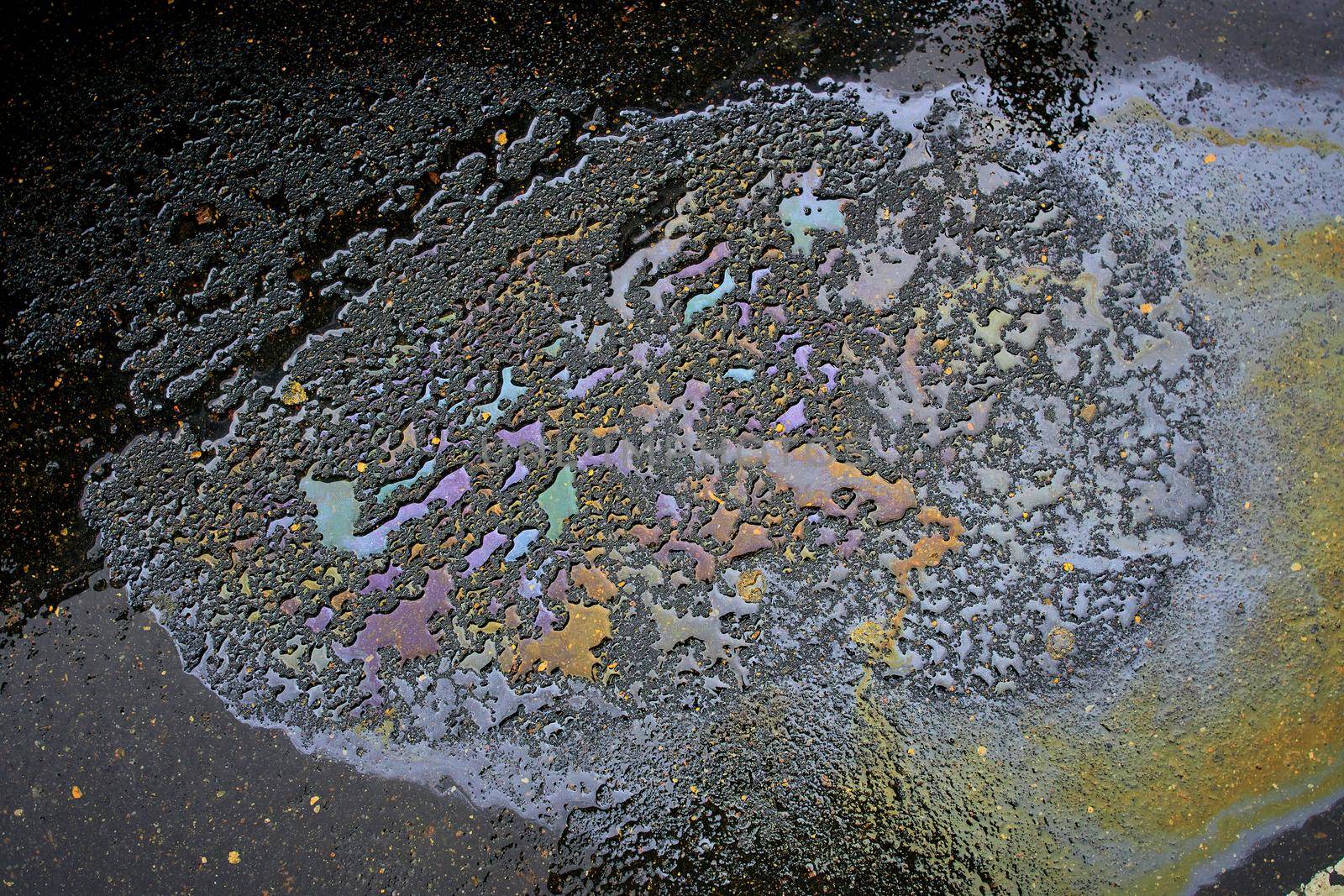 Gasoline spill on asphalt with a white dividing strip in a car park as a texture or background.