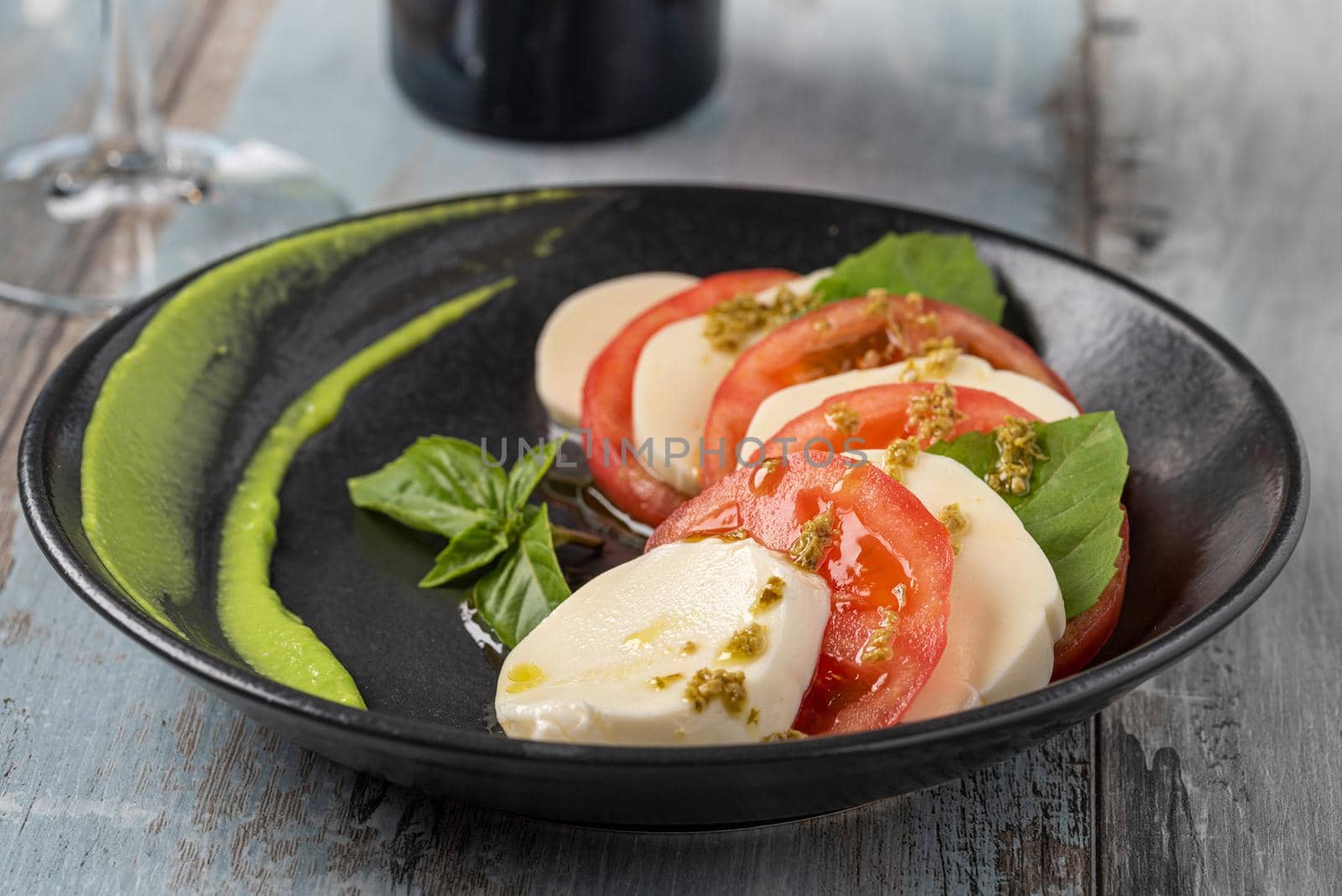 Fresh italian caprese salad with mozzarella and tomatoes on dark plate