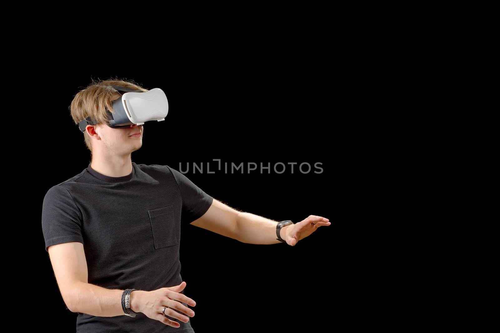 Young man wearing virtual reality VR glasses, goggles isolated on black background. Inside A Metaverse by PhotoTime