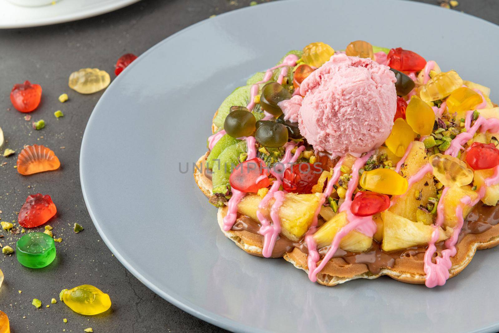 Heart waffle with kiwi and pineapple with gummy candy and ice cream on it. by Sonat