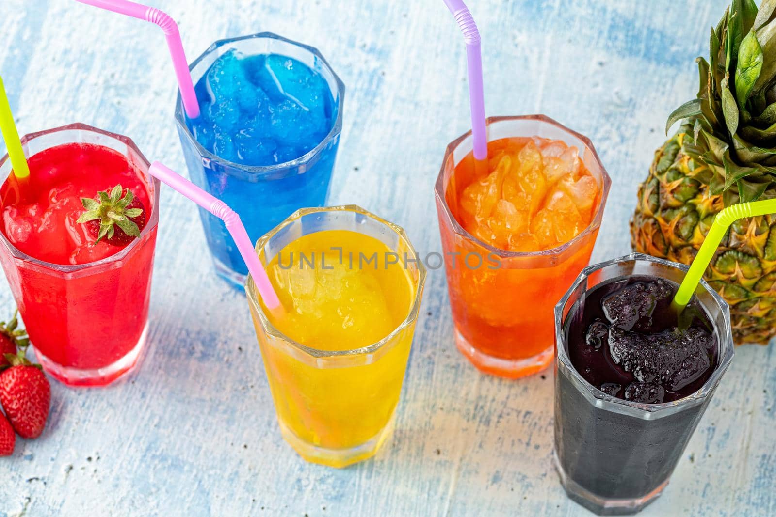 Refreshing frozens in various fruits and colors on a blue background.