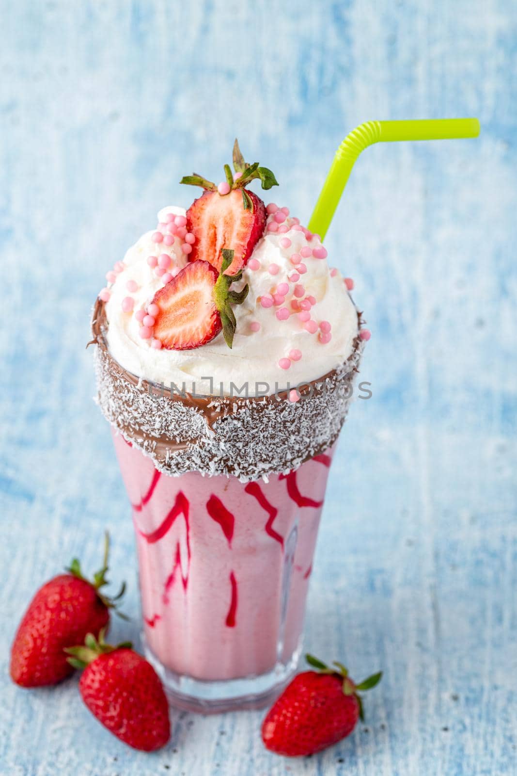 Refreshing strawberry milkshake on blue stone background