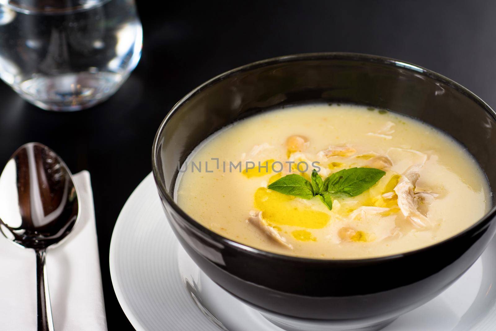 Creamy chicken soup on a black plate on a dark background.