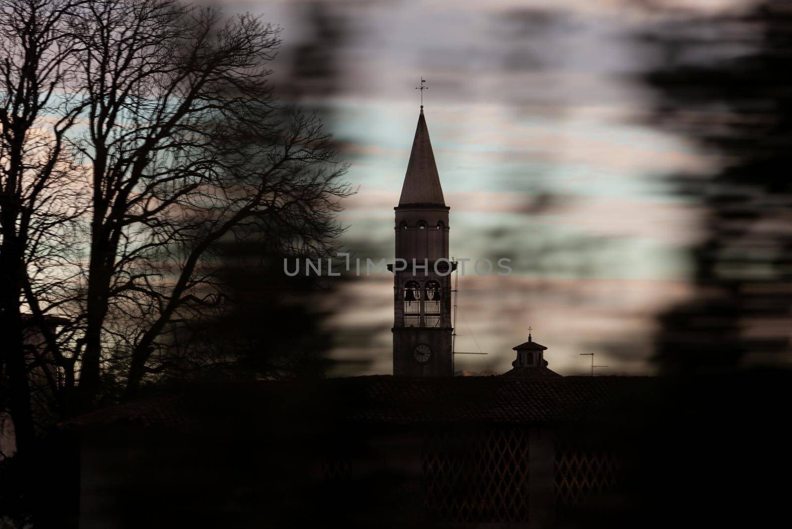 View of a bell tower from the train window. Speedy travel concept through the panning photography technique