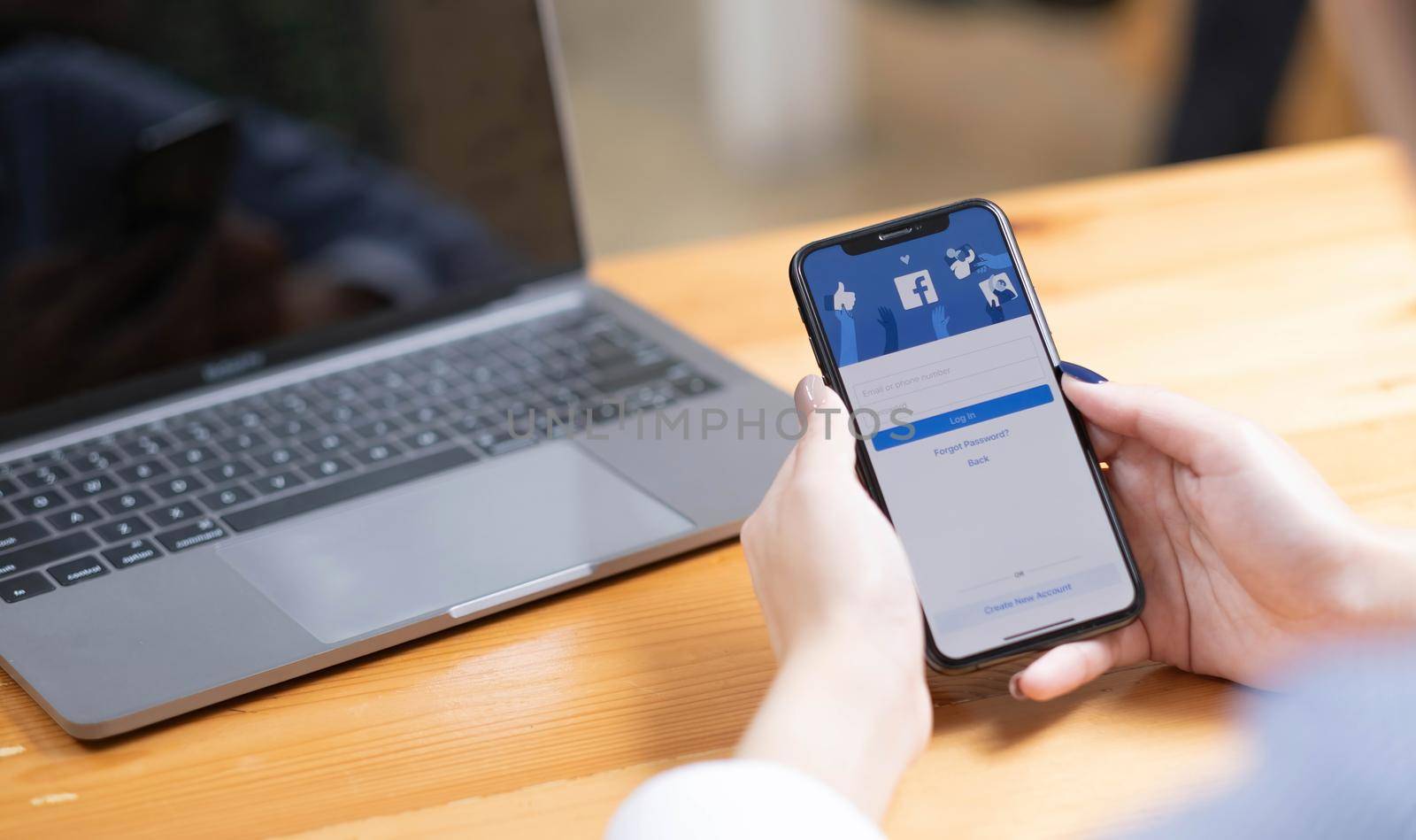 CHIANG MAI ,THAILAND - AUG 18, 2022 : Woman hand holding iPhone X to use facebook with new login screen.Facebook is a largest social network and most popular social networking site in the world. by wichayada