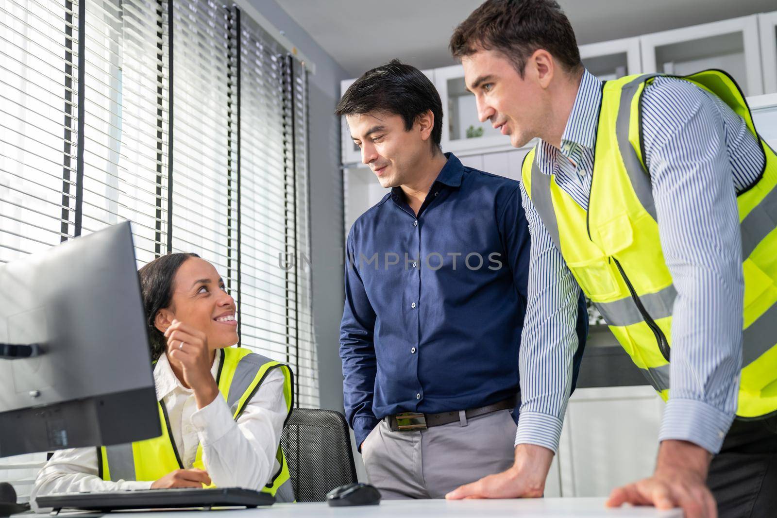 Happy multiracial team of competent engineers and investor smiles and works together at the table, cheerful and smart people brainstorming or meeting on engineering projects.