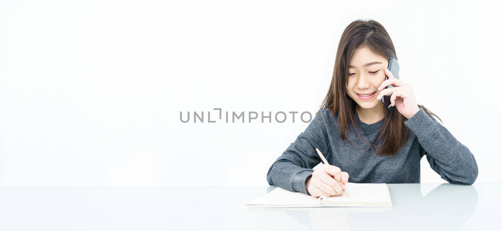 Close up woman long hair writing notebook and using mobile phone on white background