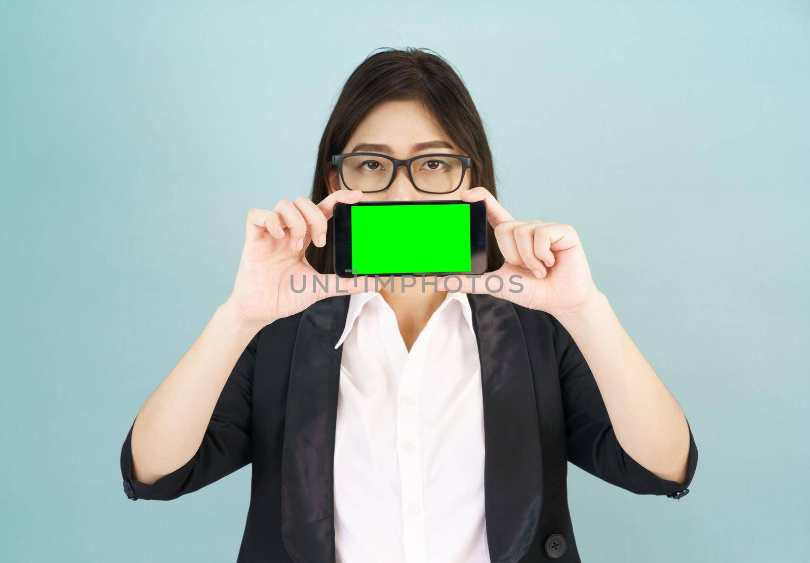 Young women in suit holding her  smartphone mock up green screen standing against blue background