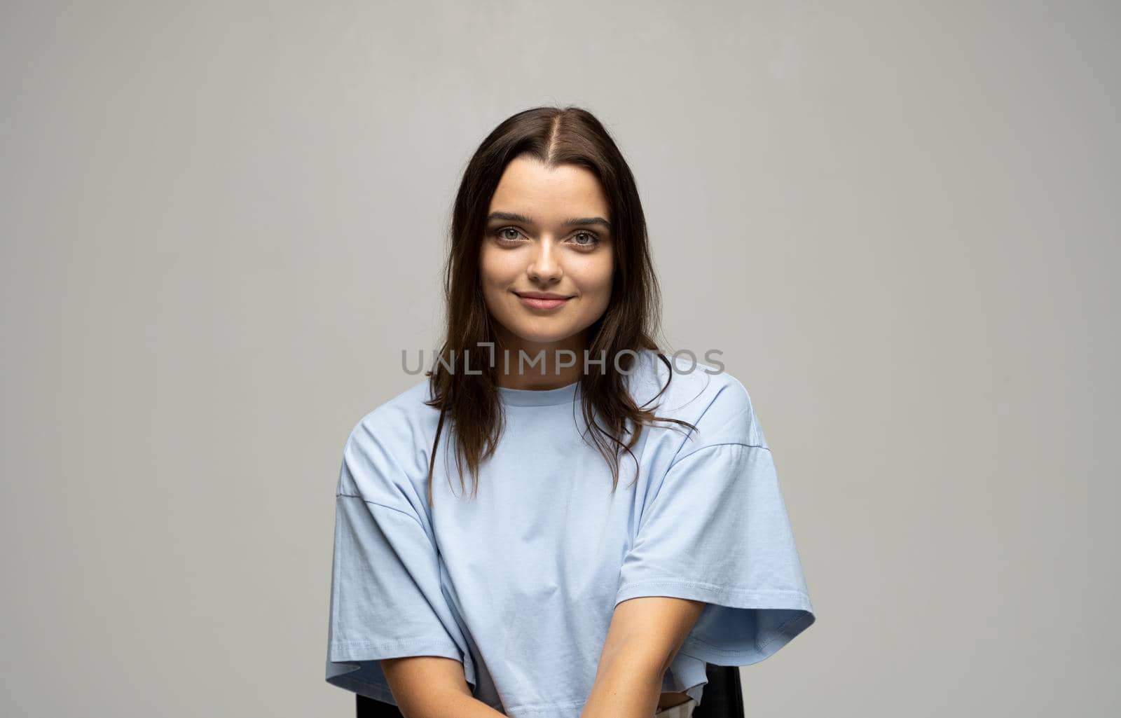 Portrait of young beautiful cute cheerful girl woman in beige t-shirt smiling looking at camera over blue background