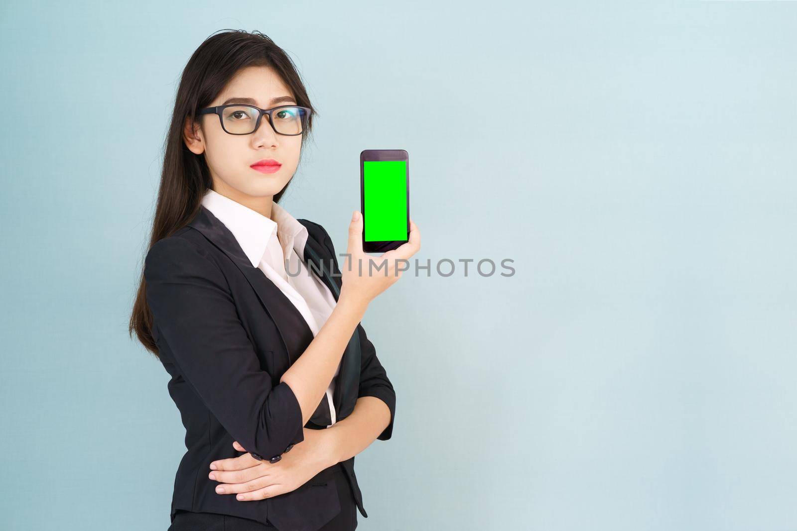 Young women in suit holding her  smartphone mock up green screen standing against blue background