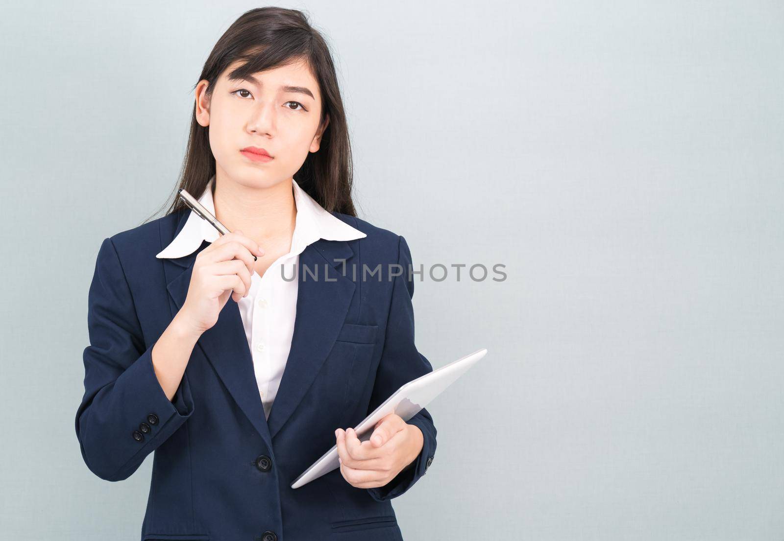 Asian woman in suit using computer digital tablet isolated on gray background