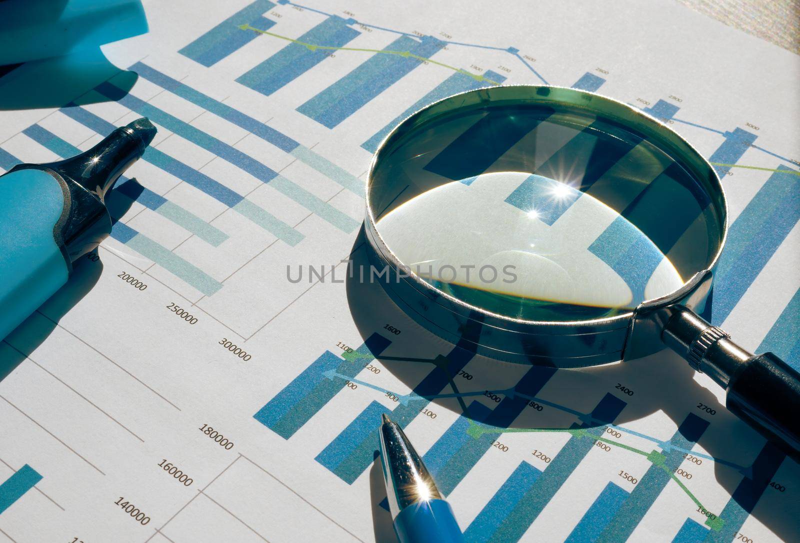 Financial charts, graphs and a magnifying glass for audit.