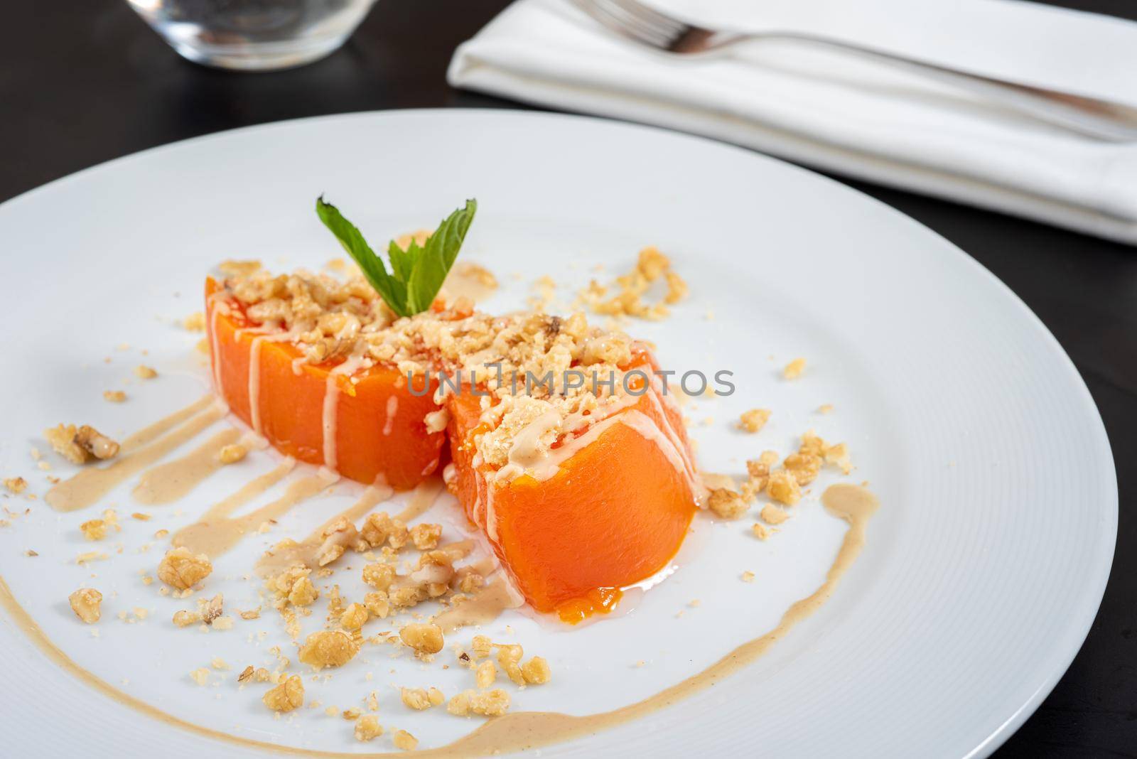 Pumpkin dessert with tahini and walnuts on a white porcelain plate