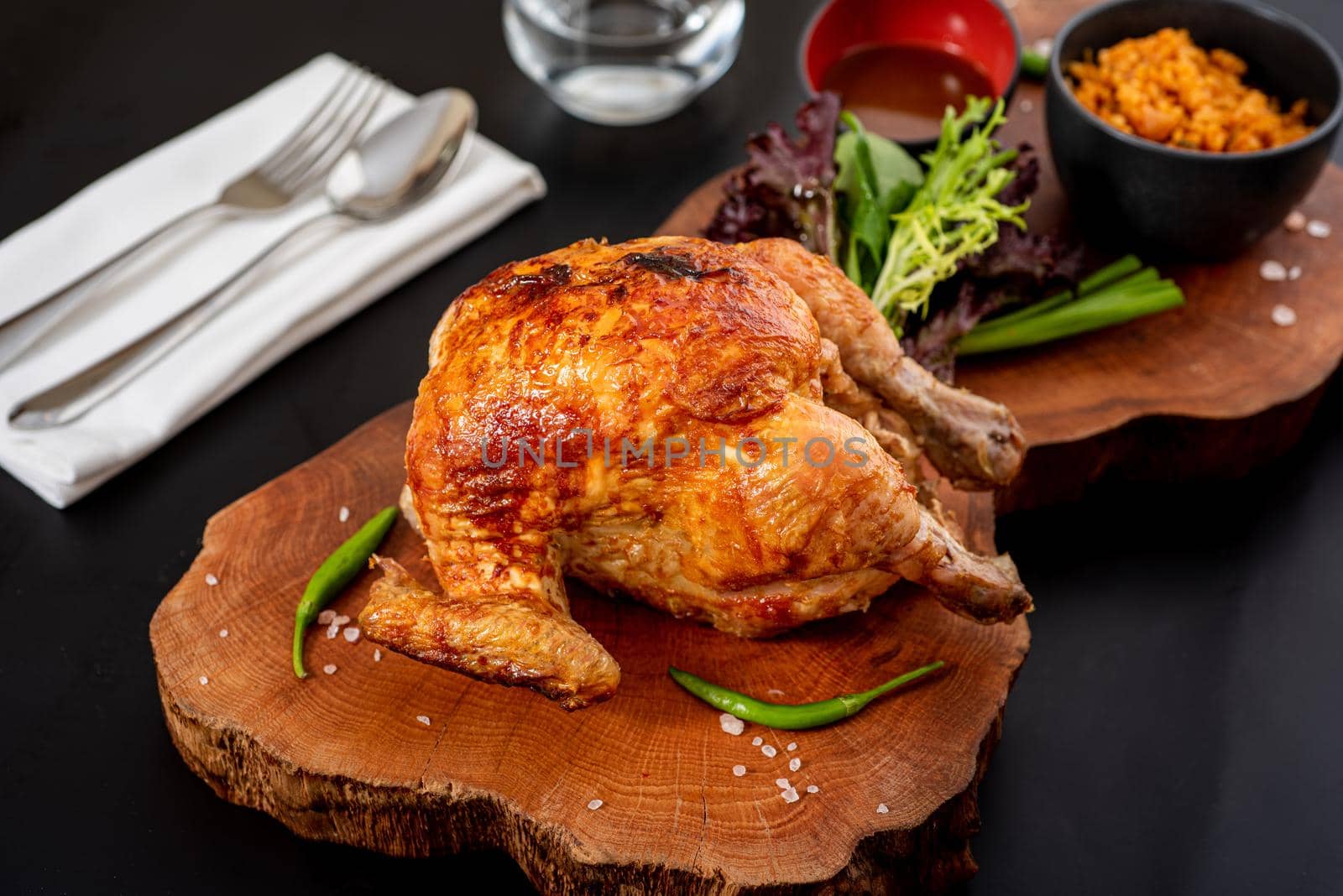 Roasted whole chicken cooked on charcoal with bulgur pilaf on wooden board.