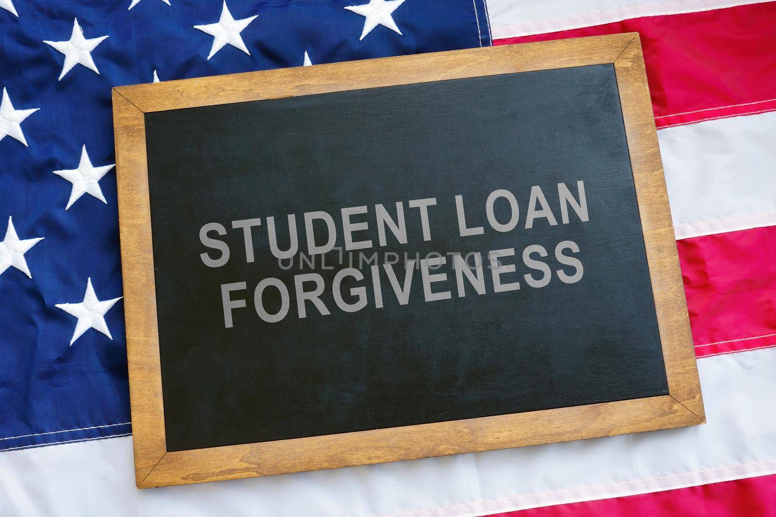 Student loan forgiveness concept. USA flag and a blackboard on it.