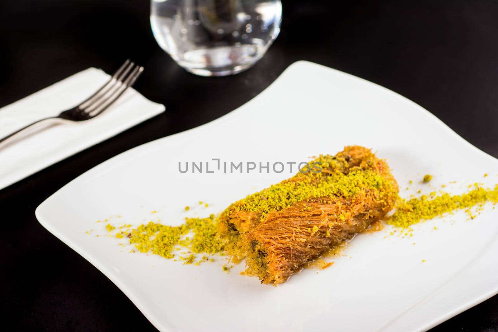 Kadayif dessert with pistachio on a white porcelain plate.