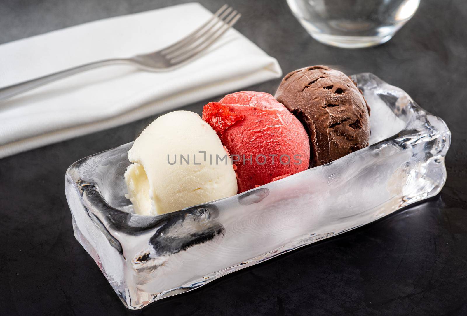 Strawberry and vanilla ice cream in ice bowl on black background.