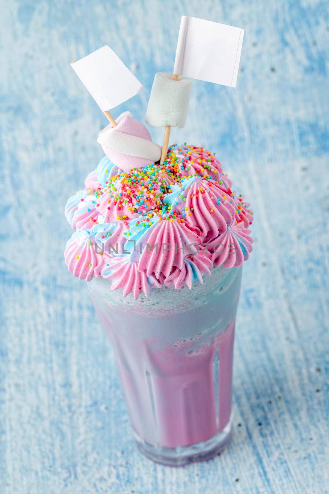 Blue and pink milkshake decorated with marshmallows on a blue background. by Sonat