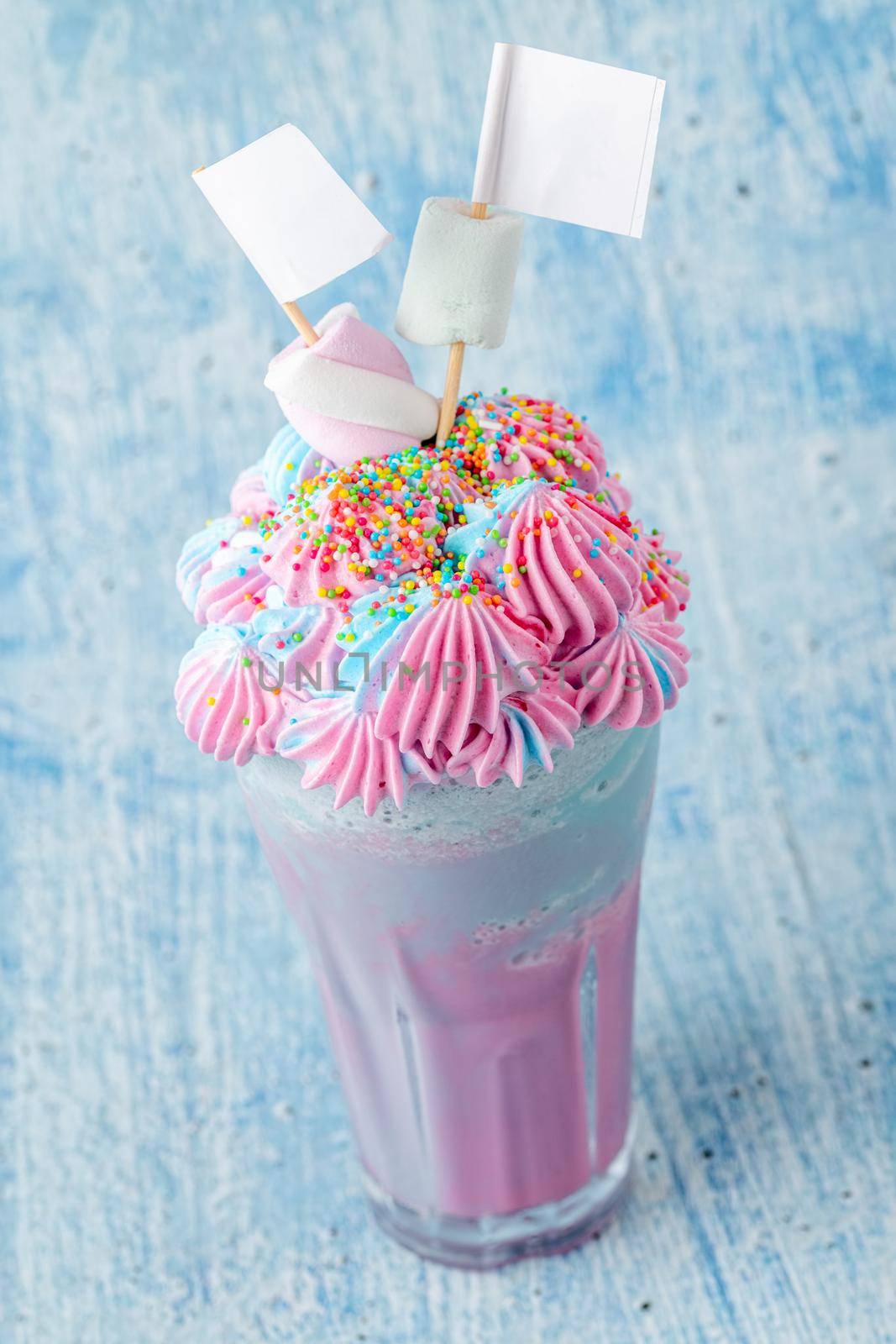 Blue and pink milkshake decorated with marshmallows on a blue background.