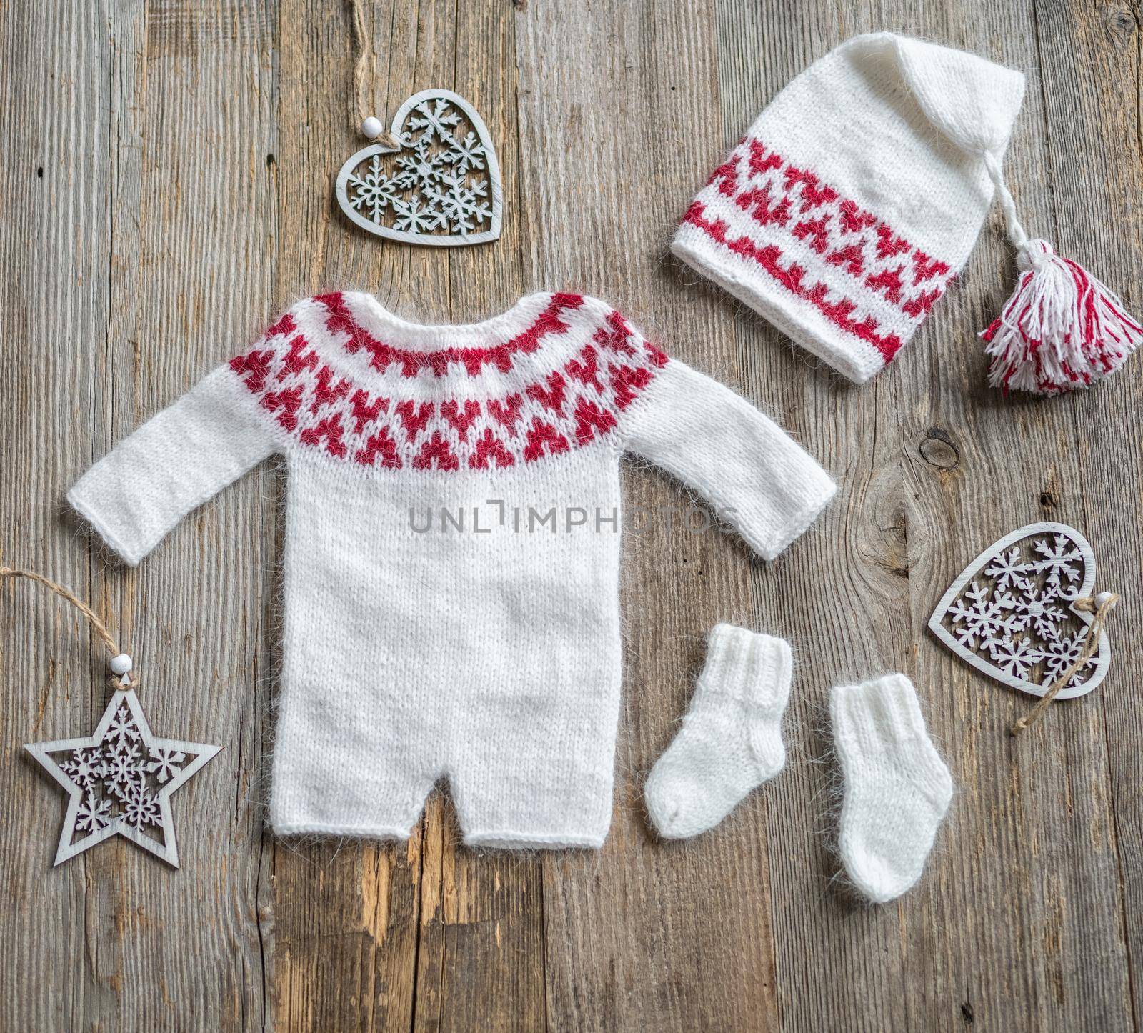 Knitted newborn hats clothes for infant studio photoshoot on wooden background closeup