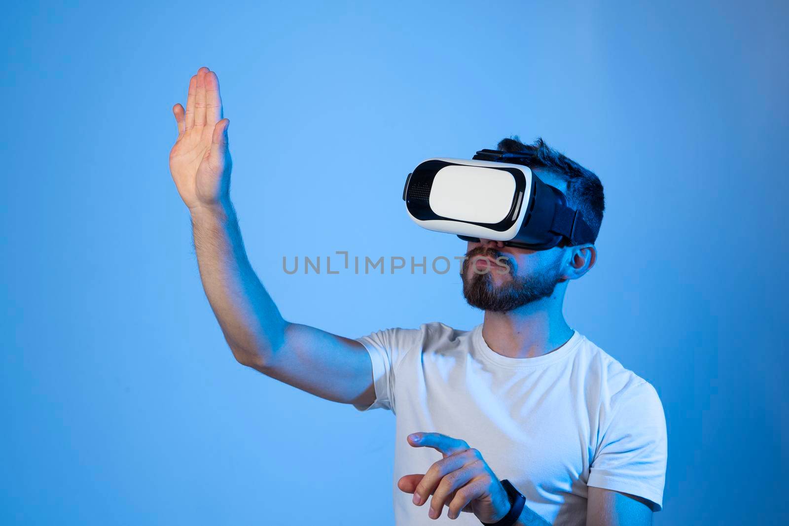 Bearded man wearing VR glasses and playing a video game with a friends in metaverse. VR technology for entertainment, learning and gaming