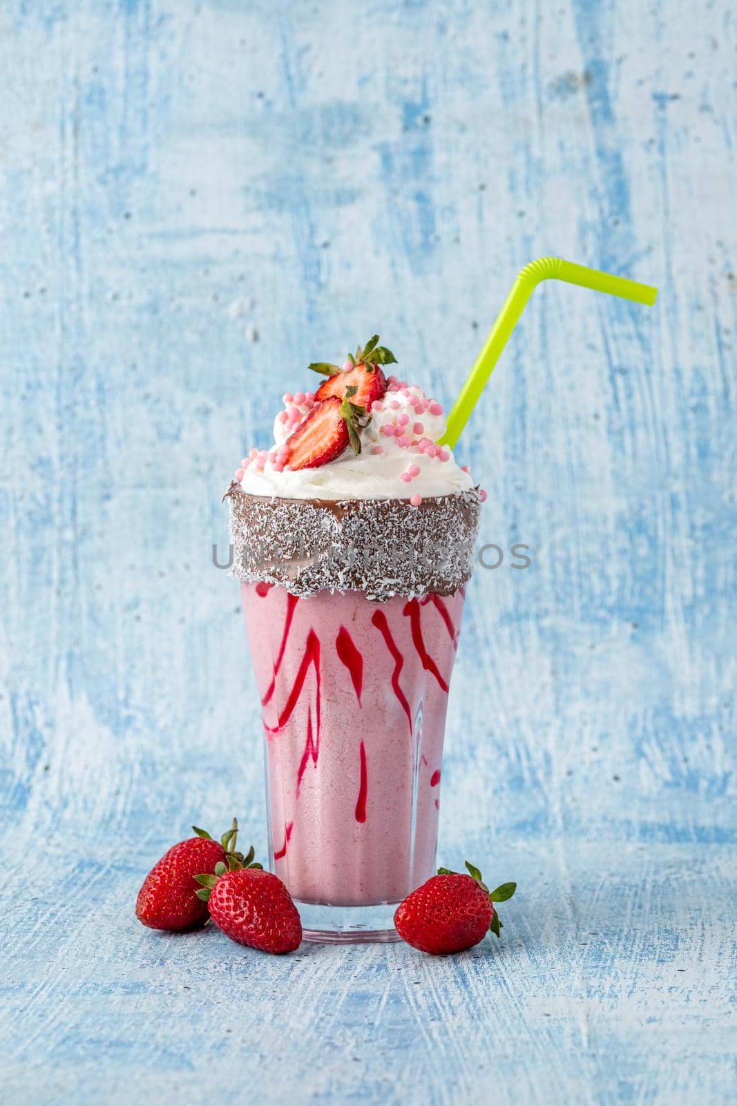 Refreshing strawberry milkshake on blue stone background