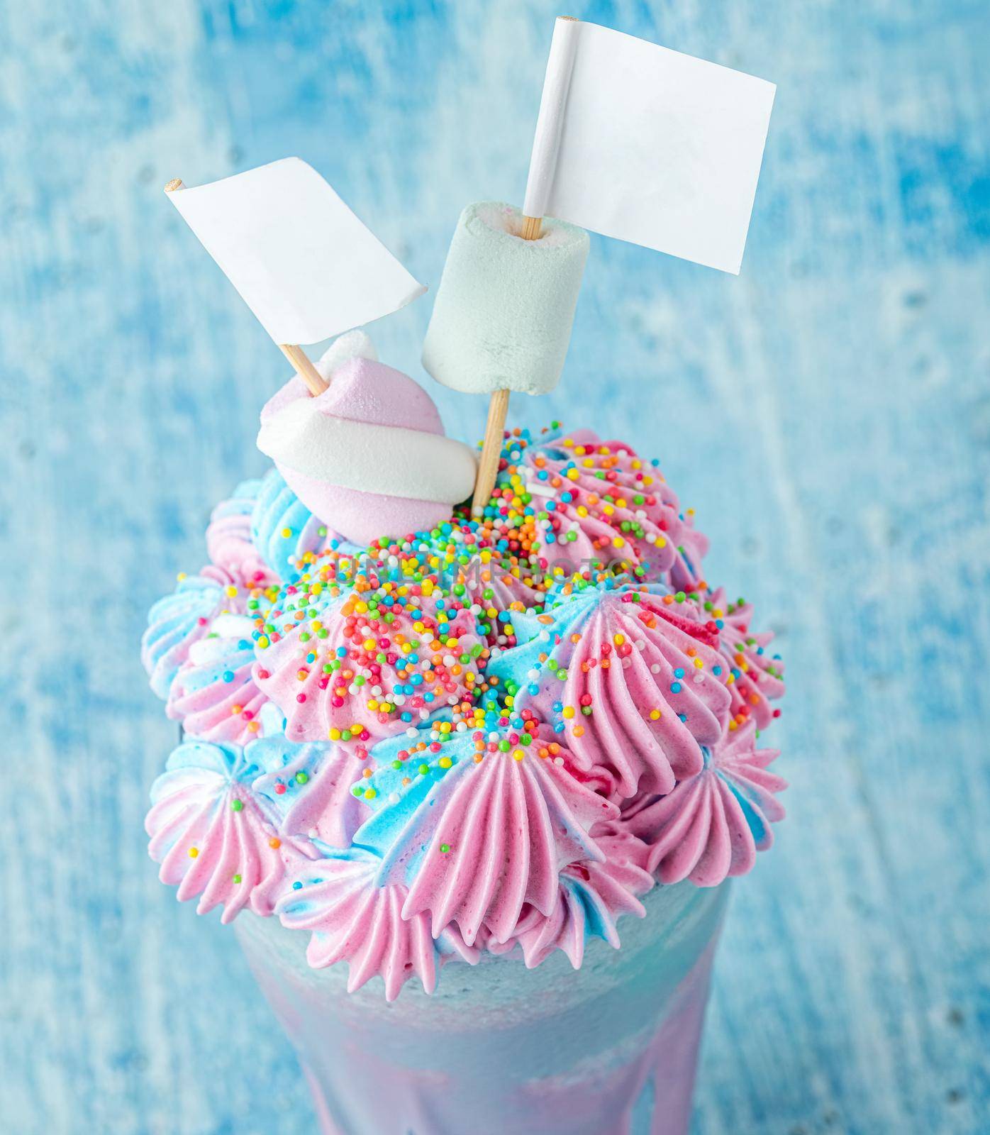 Blue and pink milkshake decorated with marshmallows on a blue background. by Sonat