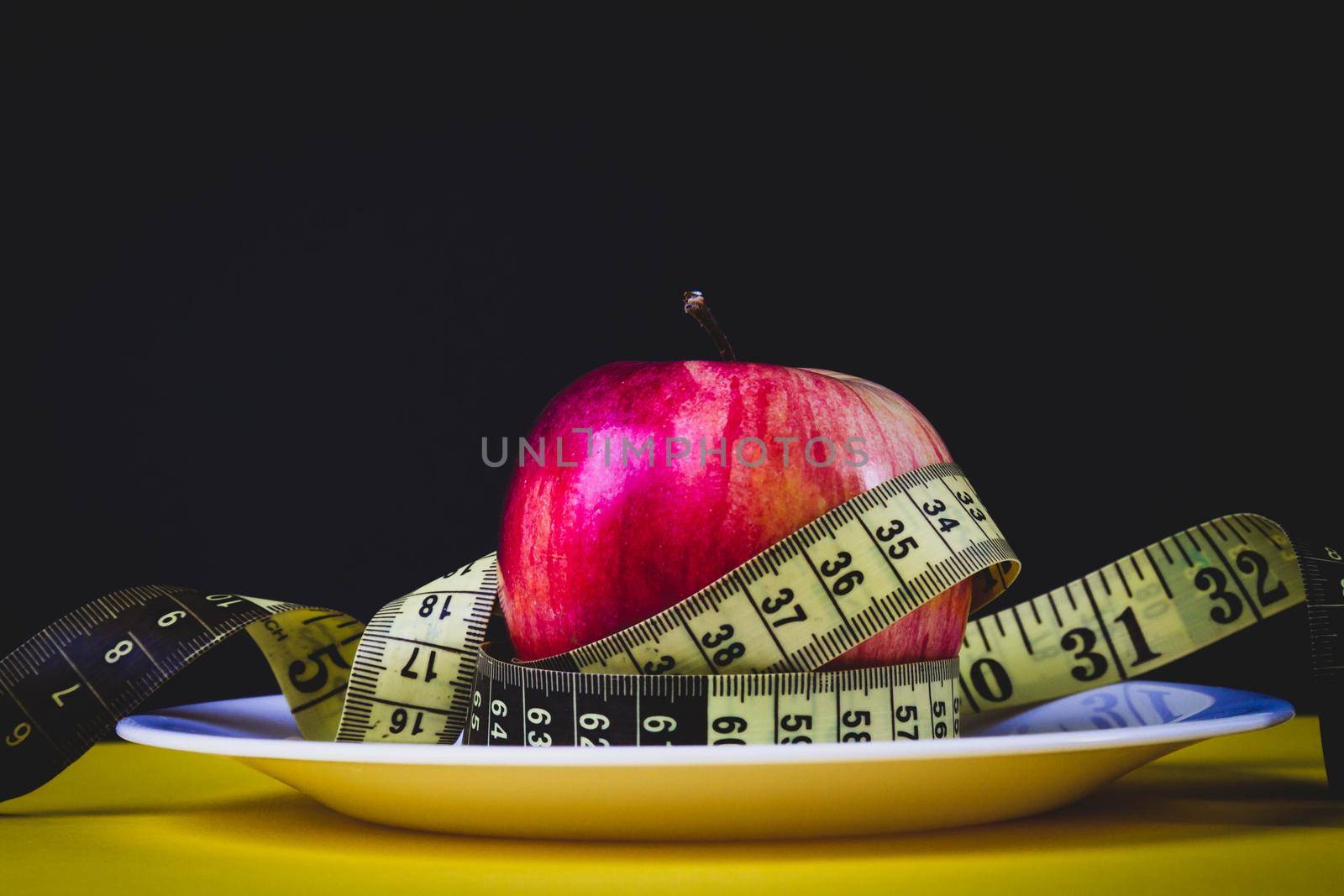 Apple as a means for weight loss. Obesity problem. Fruit diet. Apple and measuring tape.