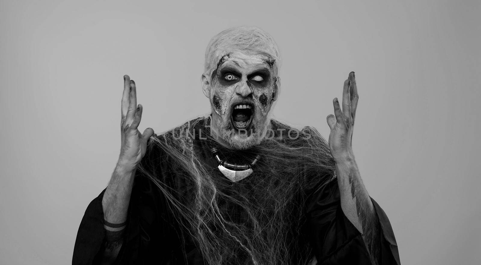 Dissatisfied frightening man with Halloween zombie bloody wounded makeup asking reason of failure, expressing disbelief irritation, feeling bored, disappointed in result, bad news. Sinister undead guy