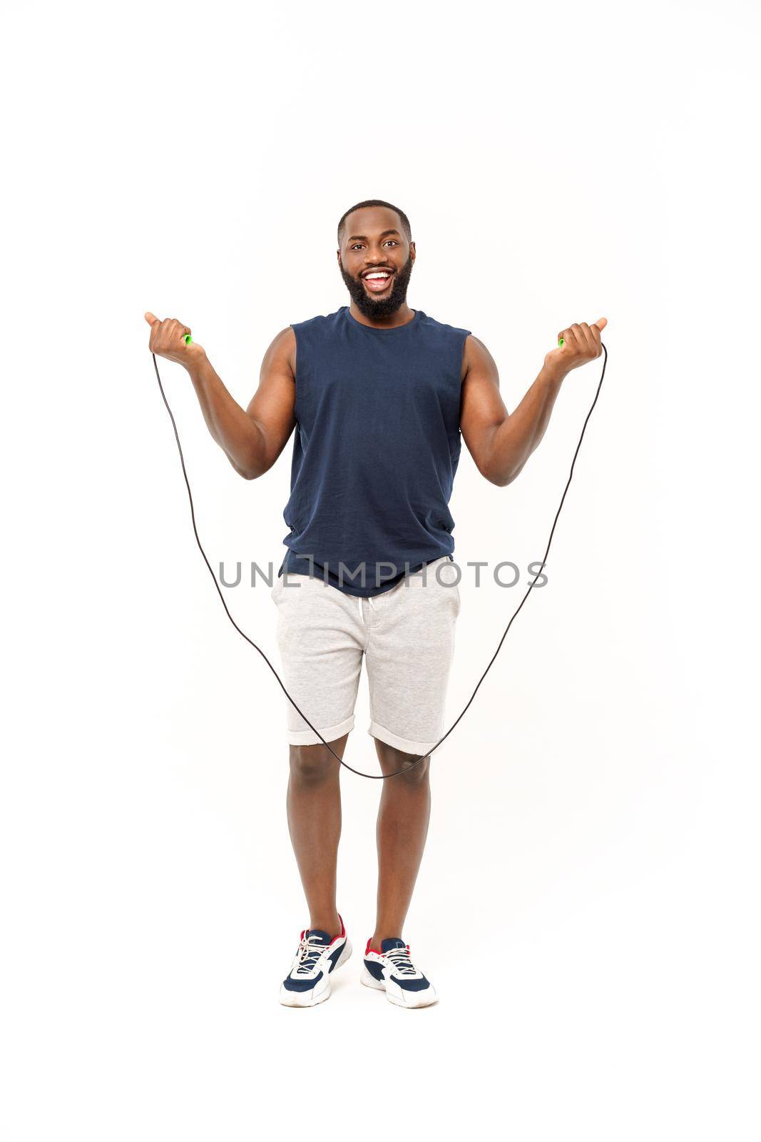 African fitness model with skipping rope against grey background. Handsome muscular man posing with jumping rope. by Benzoix
