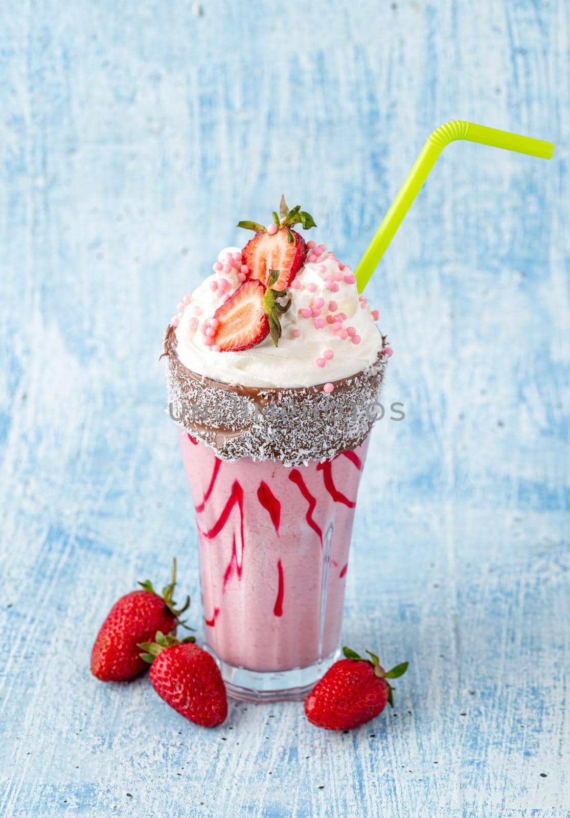 Refreshing strawberry milkshake on blue stone background