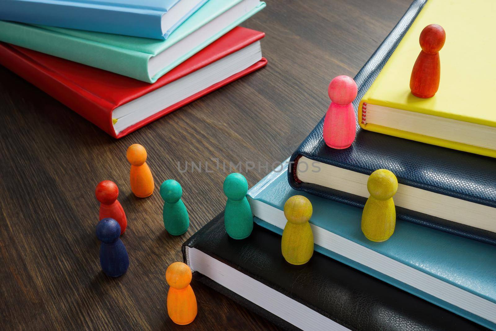 Figurines on the stairs from books. Leadership coaching style. by designer491