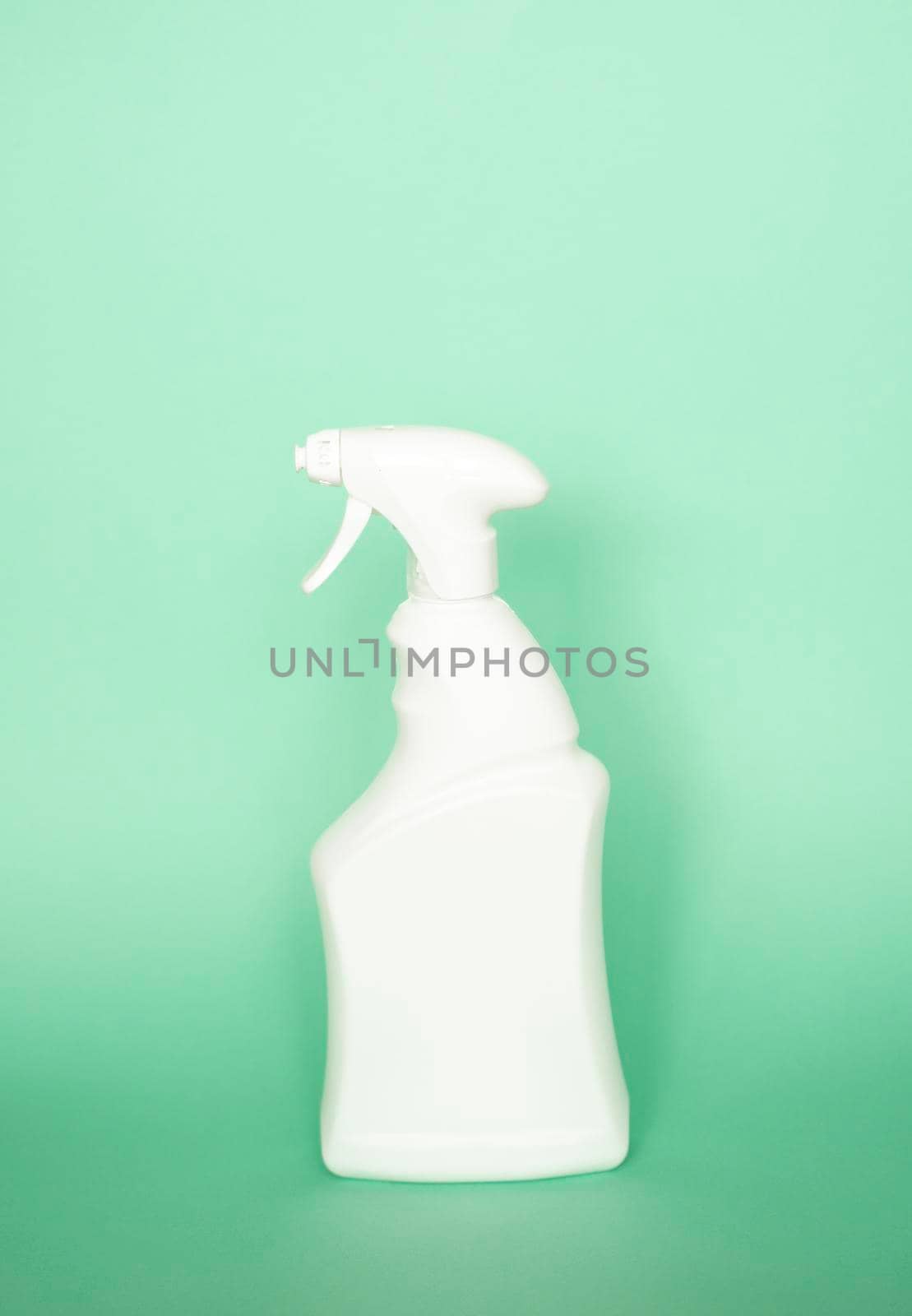 White detergent bottles or chemical cleaning supplies with a sprayer isolated on green background