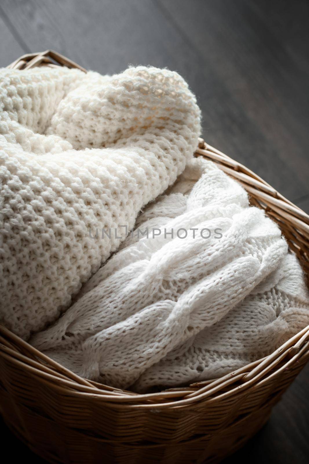 Knitted winter clothes in a basket by Anneleven